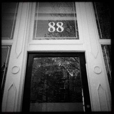 house number 88 on a glass door facade reflecting Amsterdam