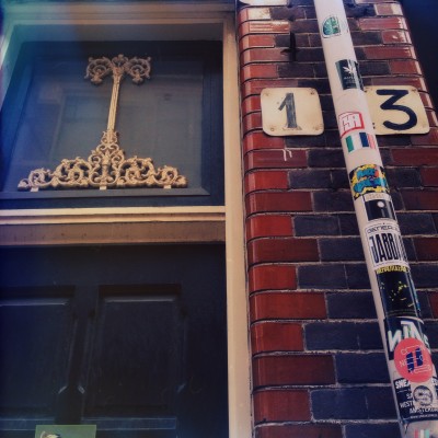 house number 13 against a brick wall next to an old fashion Amsterdam facade