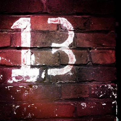 white hand written street number 13 on a brick wall in Amsterdam