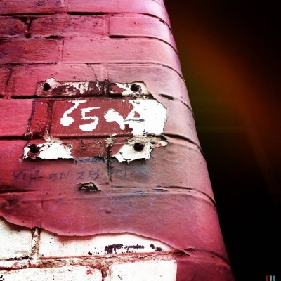 old house number 65 on a brick wall in Amsterdam