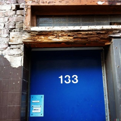 white house number 133 on a blue door in Amsterdam