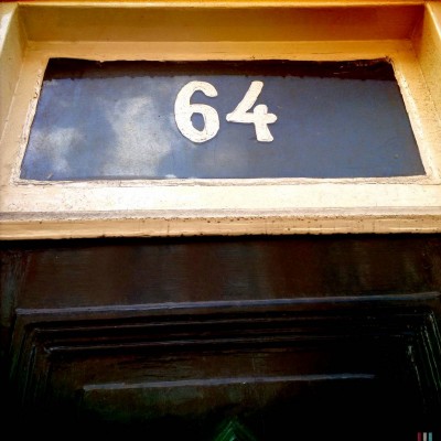 white number 64 on a door in Amsterdam