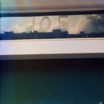 hand written house number 105 on the glass of a door facade that reflects the surroundings, in Amsterdam