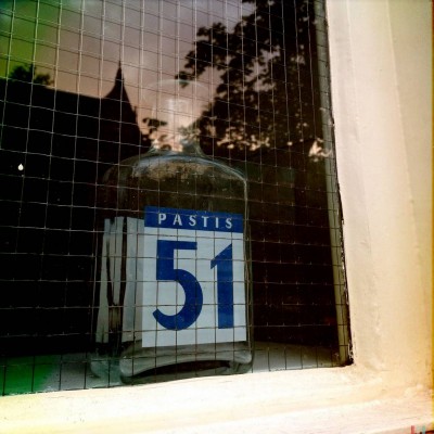 blue number 51 on an empty glass bottle of Pastis, behind a window glass, in Amsterdam