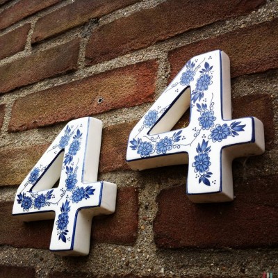 Delft blue house number 44 against a brick wall in Groesbeek