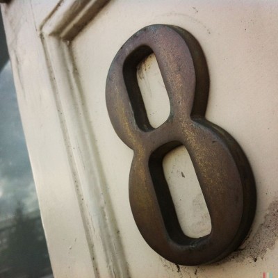 Bronze house number 8 on a white door in Amsterdam