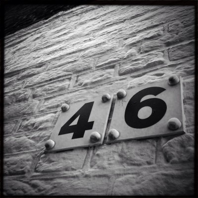 black house number 46 on a white brick wall in Amsterdam